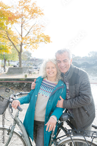 Portrait smiling senior couple bike riding along autumn river