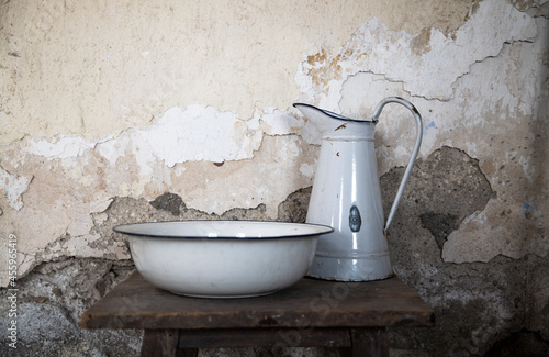 Old water basin and pitcher on wooden table against wall