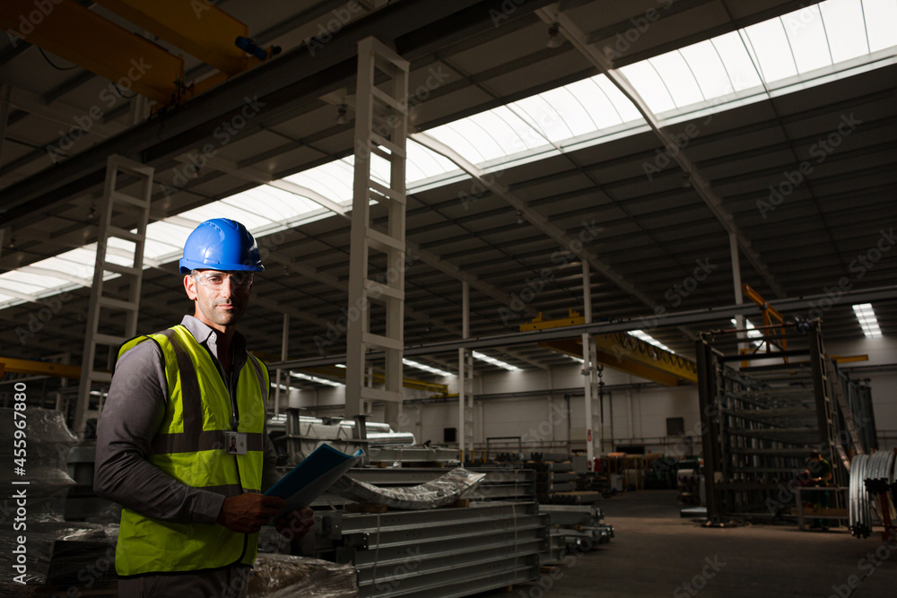 Portrait serious male worker in protective eyewear and hard-hat in factory Portrait serious male worker in protective eyewear and hard-hat in factory