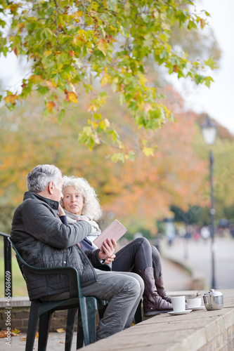 Active senior couple talking, enjoying coffee at autumn park cafe © KOTO