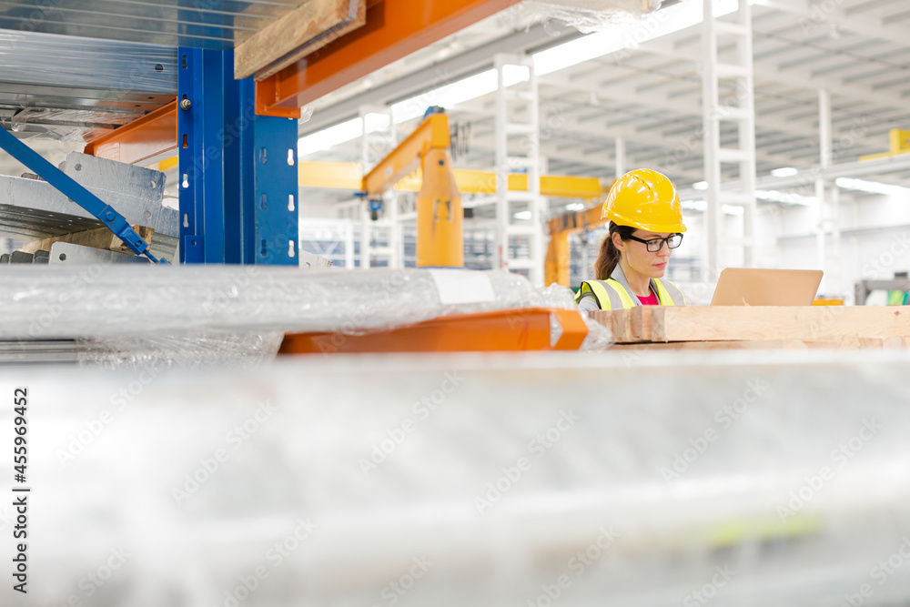 Female worker using laptop in factory Female worker using laptop in factory