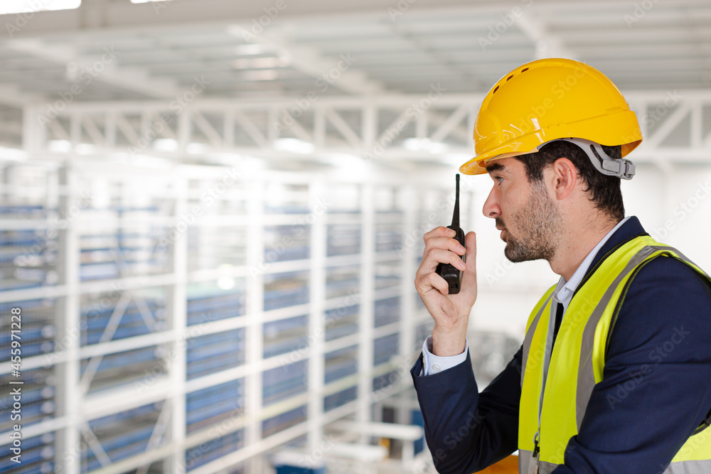 Male supervisor using walkie-talkie on platform in factory Male supervisor using walkie-talkie on platform in factory