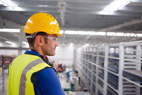 Portrait serious male worker in protective eyewear and hard-hat in factory