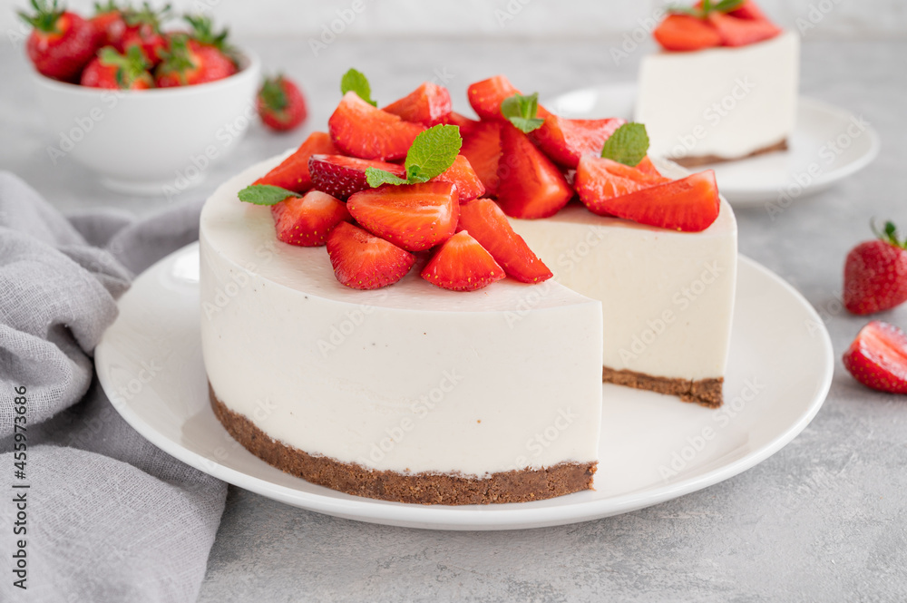 No baked cheesecake with fresh strawberries and mint on top on a white plate on a gray concrete background. Copy space. No baked cheesecake with fresh strawberries and mint on top on a white plate on a gray concrete background. Copy space.