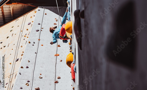 Young man professional rock climber practicing at training center in sunny day, outdoors. Concept of healthy lifestyle, tourism, nature, motion.