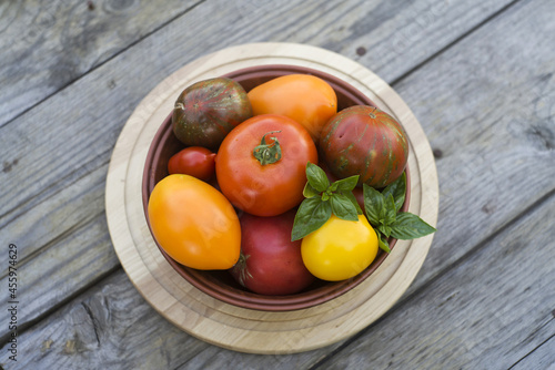 bowl with red and yellow tomatoes on gray plank wooden background.harvest time. autumn. natural food. 