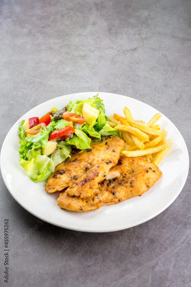 Homemade food concept. Chicken breast steak with black pepper served with salad and french fries in a white dish. Hight protein food. Homemade food concept. Chicken breast steak with black pepper served with salad and french fries in a white dish. Hight protein food.