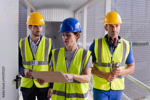 Supervisors and worker with clipboard in factory