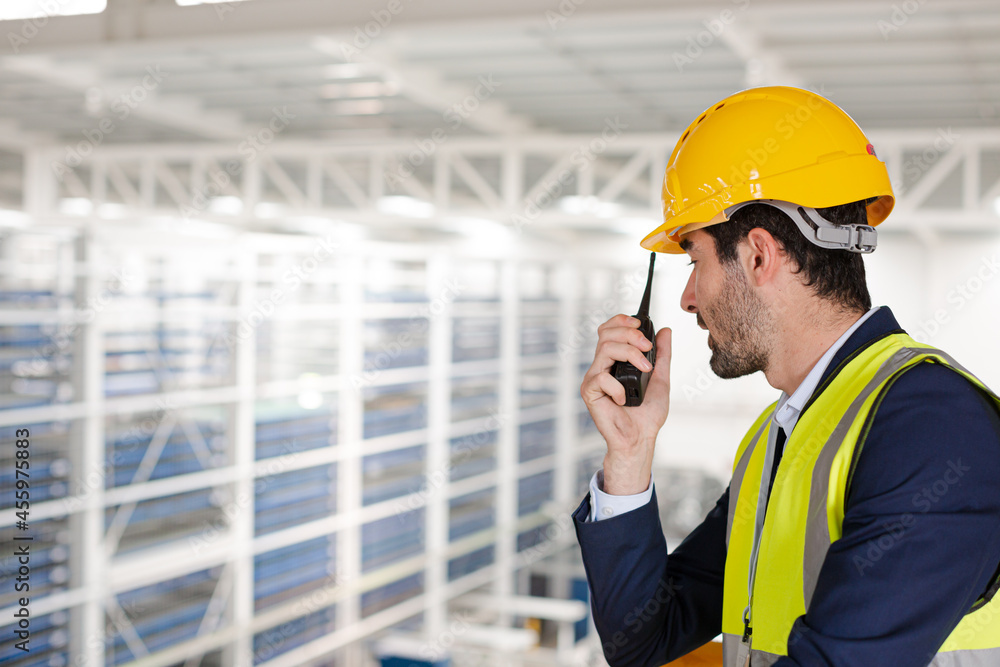 Male supervisor using walkie-talkie on platform in factory Male supervisor using walkie-talkie on platform in factory