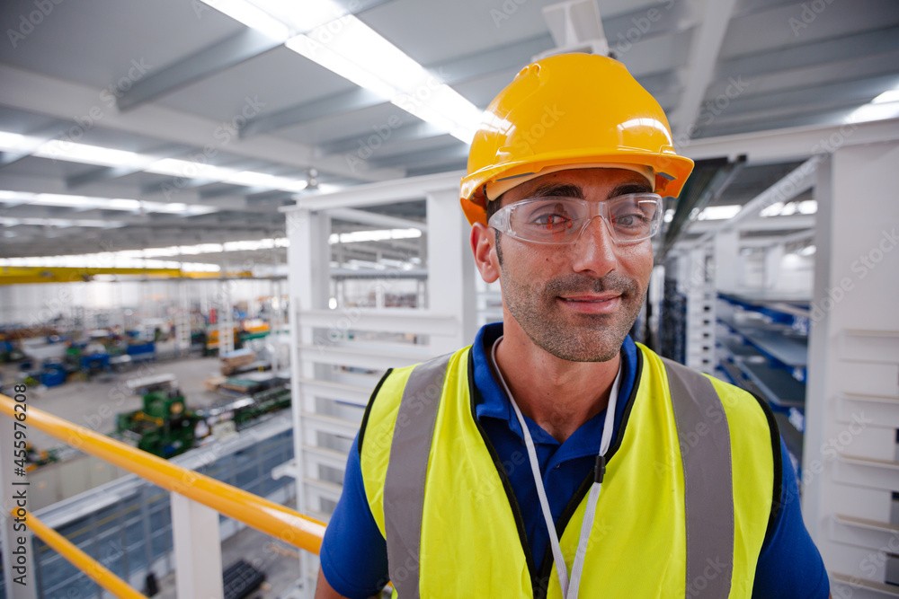 Portrait serious male worker in protective eyewear and hard-hat in factory Portrait serious male worker in protective eyewear and hard-hat in factory