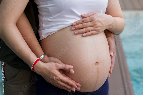 Man holding belly of his pregnant wife . Close up of a pregnant woman.