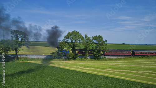 Obraz na plátne Thomas the tank engine pulling passenger cars and blowing smoke on a beautiful s