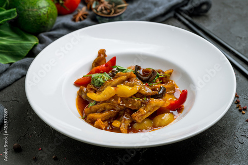 Spicy fragrant eggplant Chinese cuisine on white plate on black stone table photo