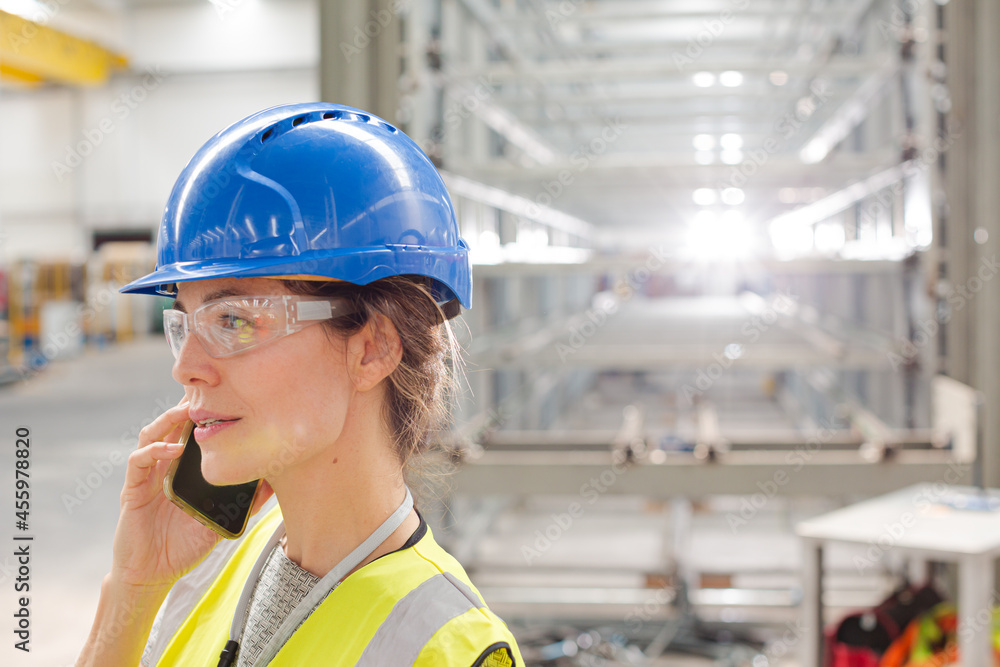 Close up female worker talking on smart phone in factory Close up female worker talking on smart phone in factory
