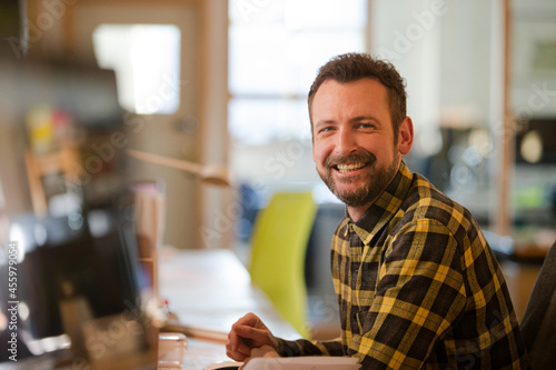 Portrait of young man posing in office, smiling