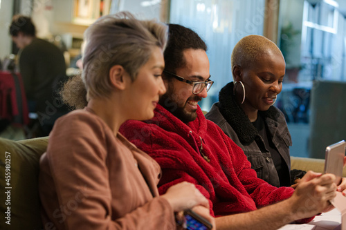 Wallpaper Mural Three colleagues sitting on sofa, discussing paperwork, laughing Torontodigital.ca
