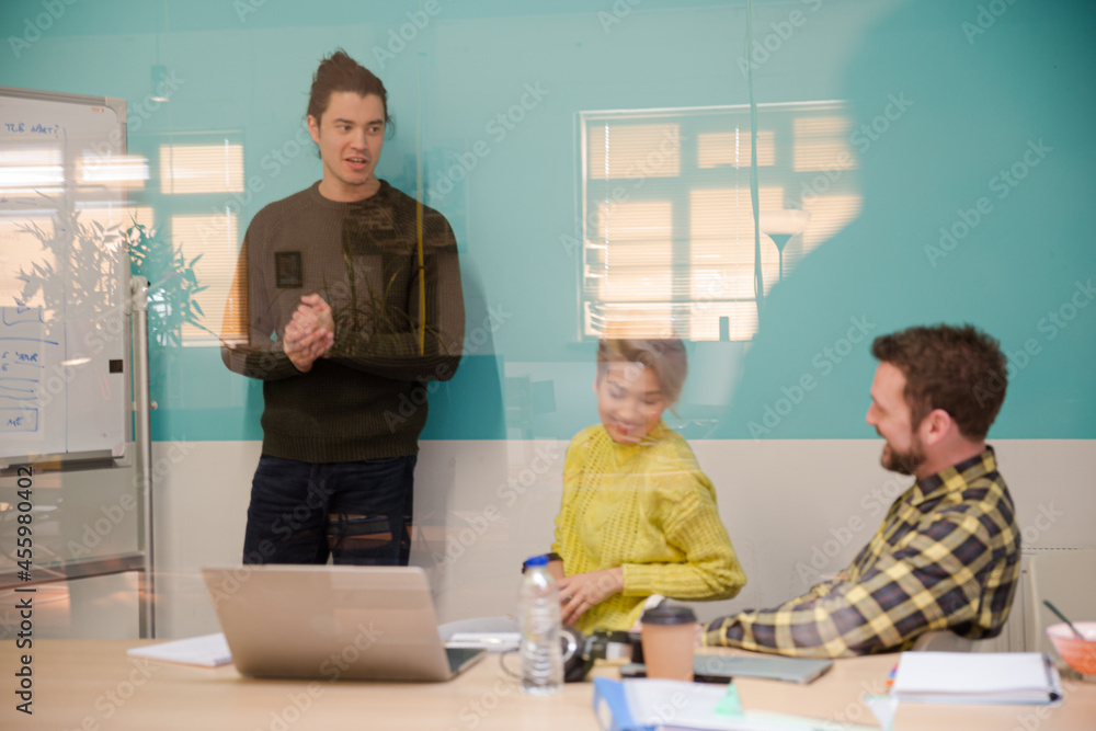 Man standing at whiteboard, leading conference room meeting Man standing at whiteboard, leading conference room meeting