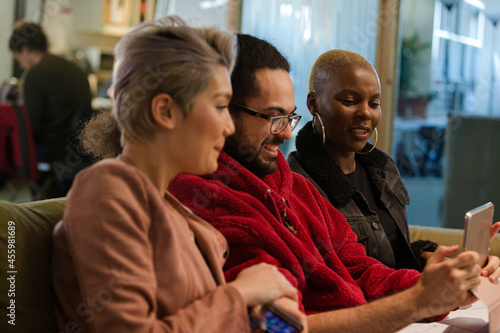 Wallpaper Mural Three colleagues sitting on sofa, discussing paperwork, laughing Torontodigital.ca