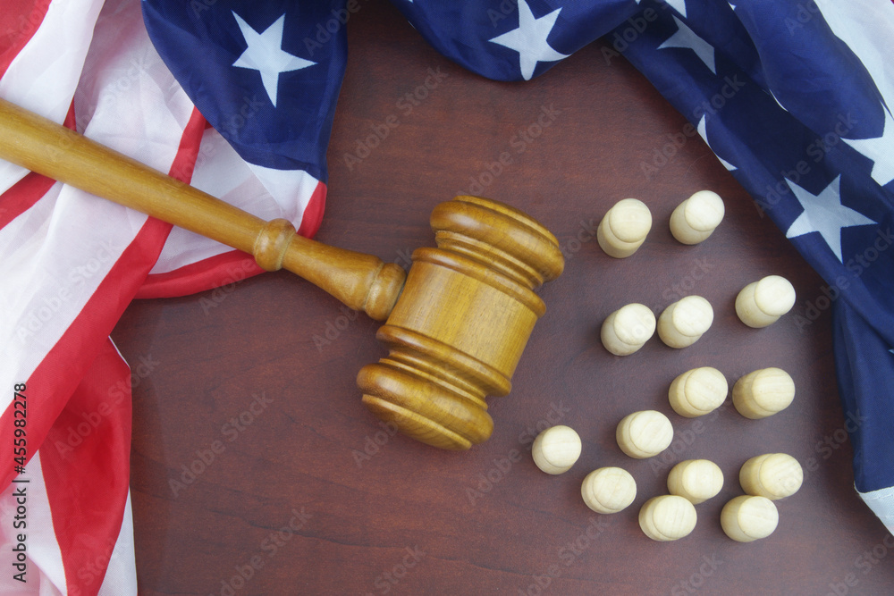 Wooden figures of people, United States flag and judge gavel om table.	