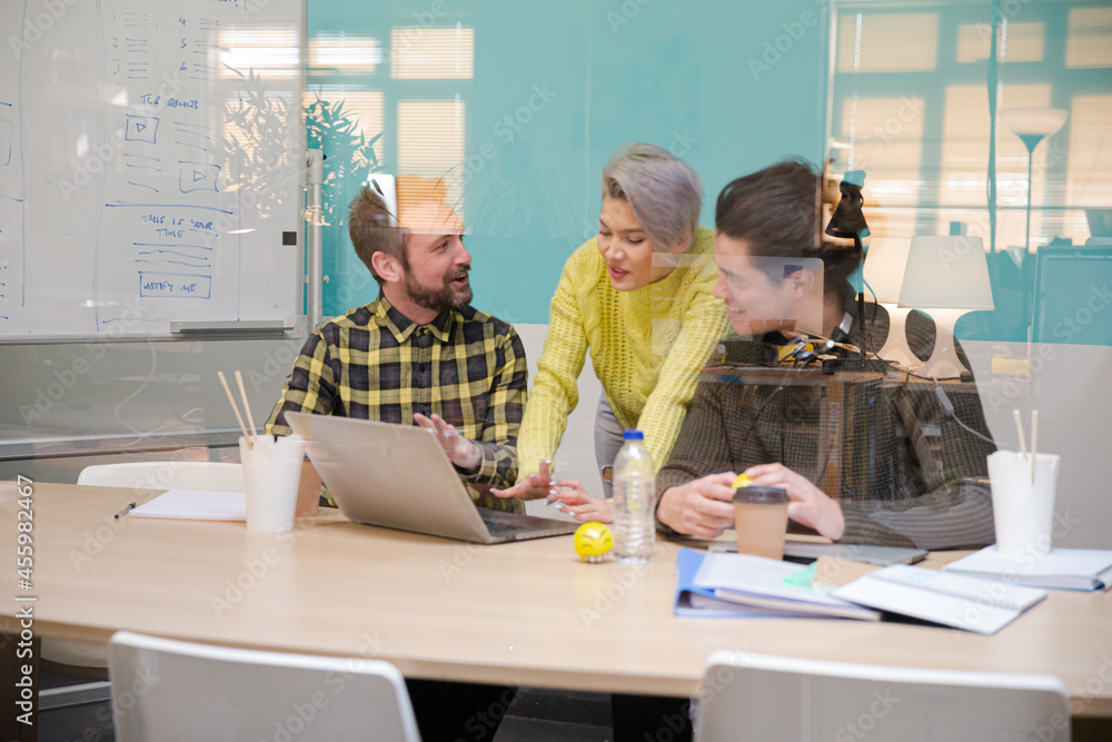 Three colleagues working at computer in conference room Three colleagues working at computer in conference room