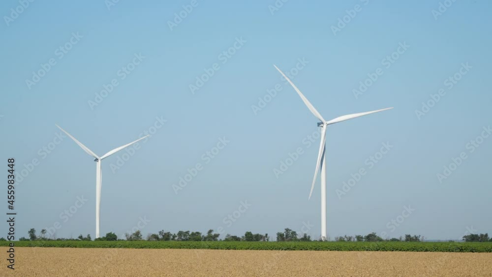 Wind turbines against the blue sky. Wind turbines are located among agricultural fields Wind turbines against the blue sky. Wind turbines are located among agricultural fields