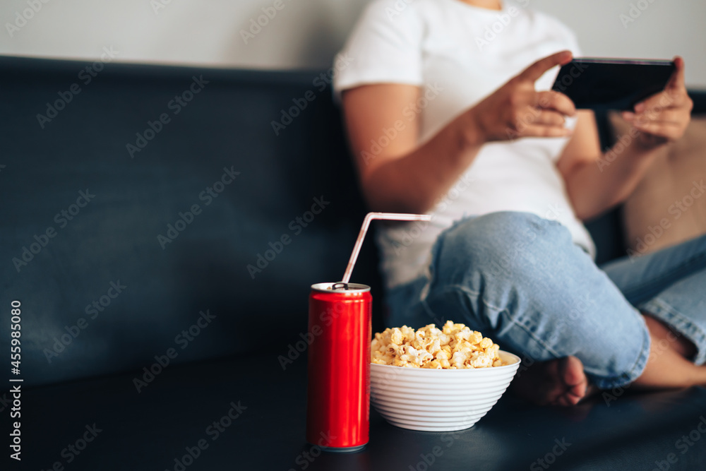 Juice can with straw and cup with popcorn in front of girl holding smartphone. Juice can with straw and cup with popcorn in front of girl holding smartphone.