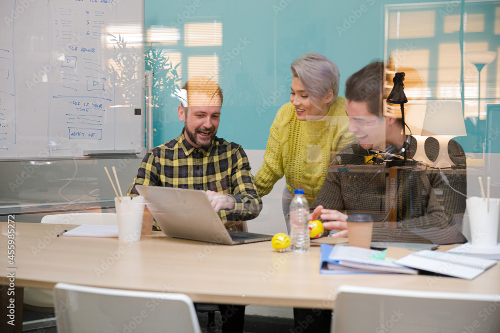Three colleagues working at computer in conference room Three colleagues working at computer in conference room