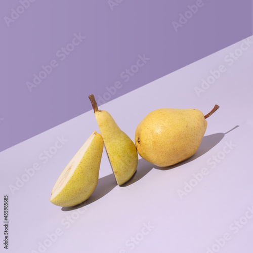 Minimal modern design with yellow pear fruit leaning aslope on purple background