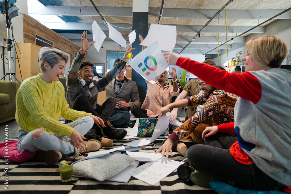Team sitting on office floor, discussing paperwork Team sitting on office floor, discussing paperwork