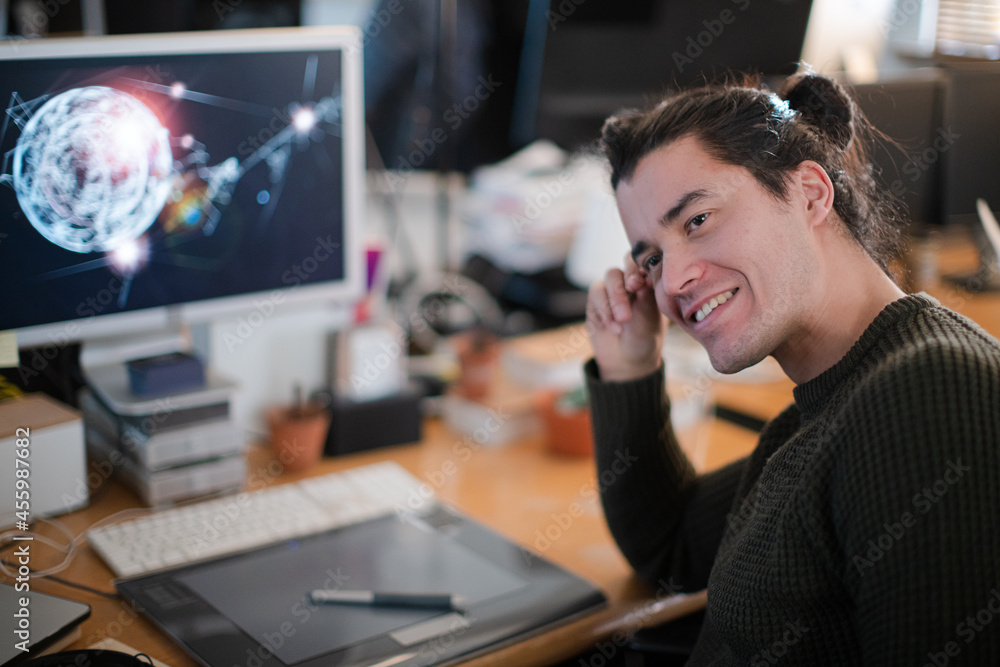 Smiling young man with long hair, working at computer Smiling young man with long hair, working at computer