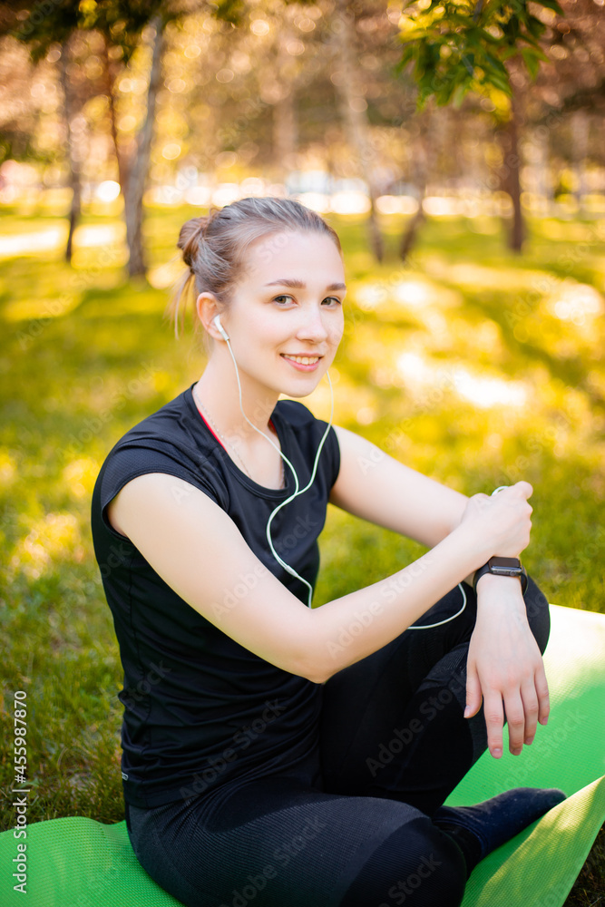 Young sportive woman sits in the park and listens to music on headphones. Young sportive woman sits in the park and listens to music on headphones.