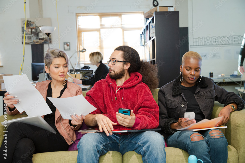 Obraz premium Smiling friends working together on sofa