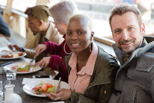 Portrait of smiling friends eating at restaurant outdoor patio