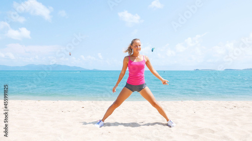 Fitness sport woman doing sporty exercise on beach outside at sunset. Healthy lifestyle image of beautiful young asian woman jogging on black sand beach.