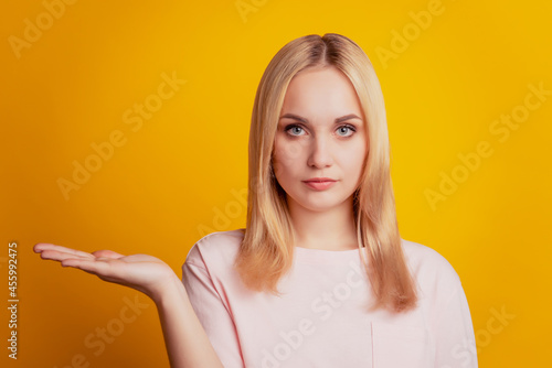 Portrait of serious promoter girl hand hold copy space on yellow background