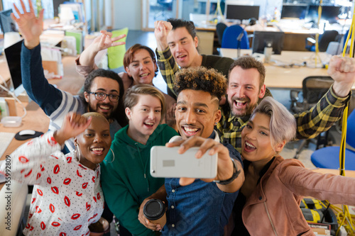 Team talking group selfie with smartphone in office