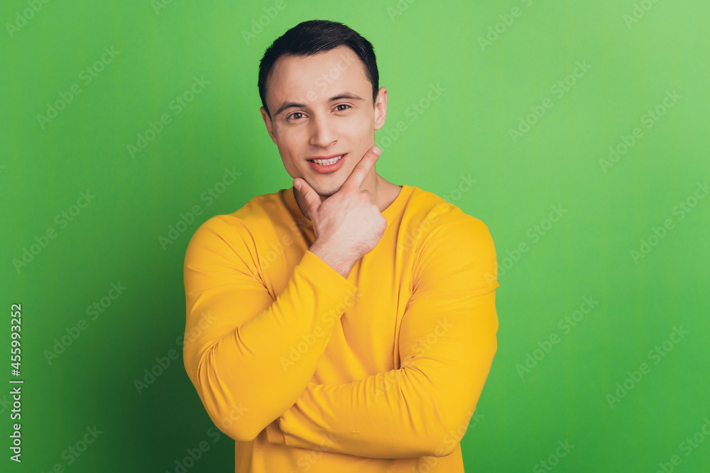 Portrait of positive thoughtful guy finger chin think on green background