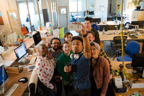 Team taking group selfie with smartphone in office