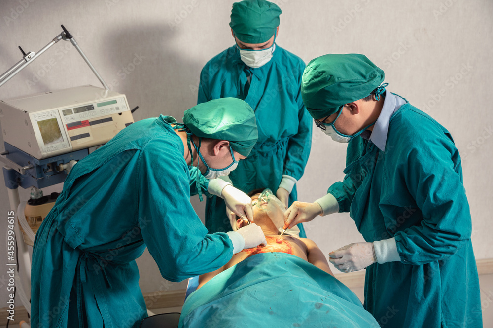 Surgeons team in surgical gown performing surgery a seriously injured patient in operating room at hospital Surgeons team in surgical gown performing surgery a seriously injured patient in operating room at hospital