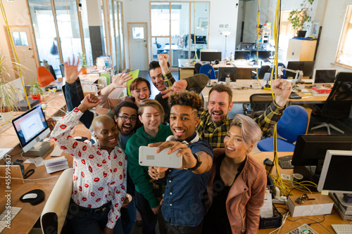 Team talking group selfie with smartphone in office