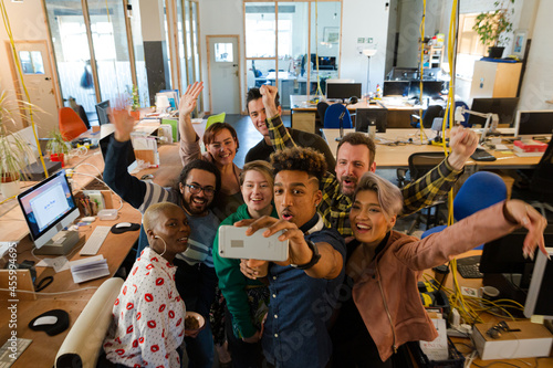 Team talking group selfie with smartphone in office