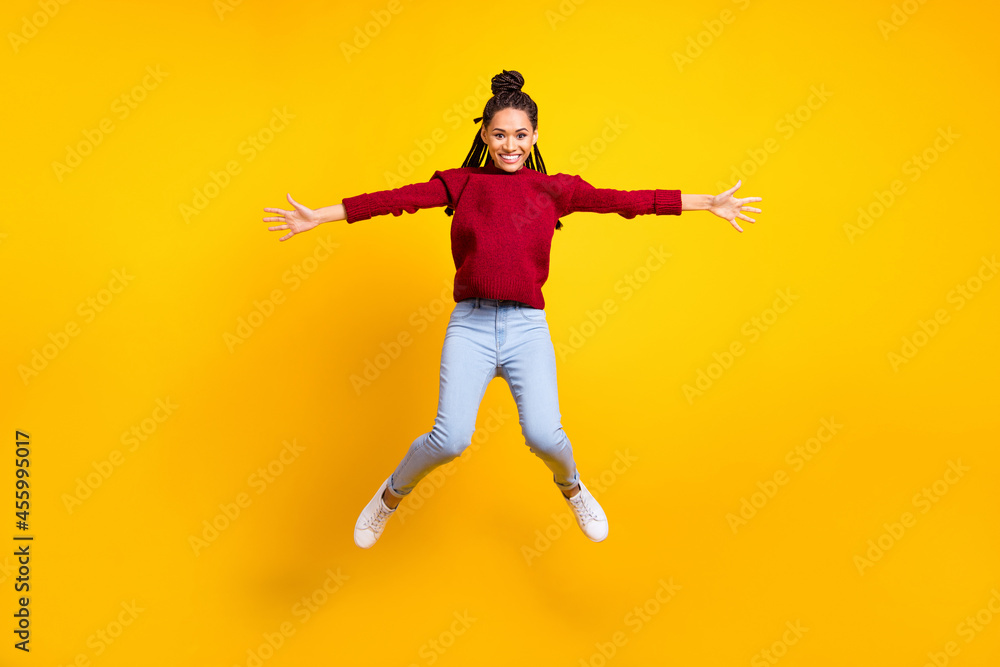 Full length photo of sweet cute dark skin lady wear red pullover smiling jumping high isolated yellow color background
