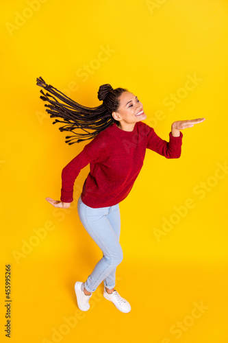 Vertical full length photo of sweet funny dark skin lady wear red pullover smiling dancing isolated yellow color background photo