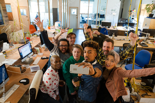 Team taking group selfie with smartphone in office