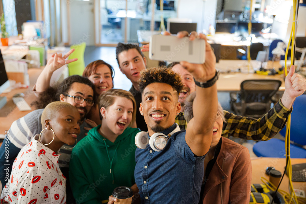 Obraz premium Team taking group selfie with smartphone in office
