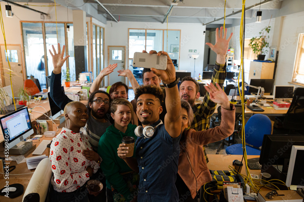 Team taking group selfie with smartphone in office Team taking group selfie with smartphone in office