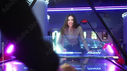 A beautiful woman playing game of table hockey with her boyfriend inside a game arcade. Show sad emotions because lose the game. photo