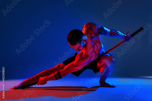 athlete men silhouette with stick training karate using sports tool in studio on colorfull lights background