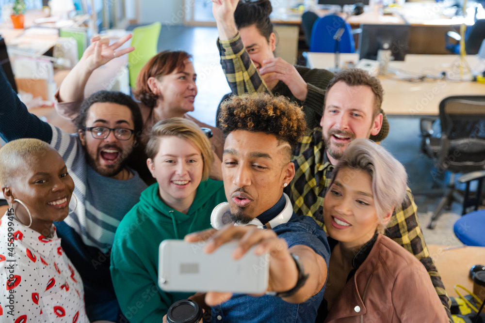 Team taking group selfie with smartphone in office