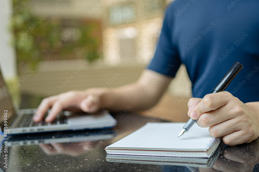 Online studying concept the man who is working from home attempting to write the meeting report down while online meeting of his company is conducting Online studying concept the man who is working from home attempting to write the meeting report down while online meeting of his company is conducting
